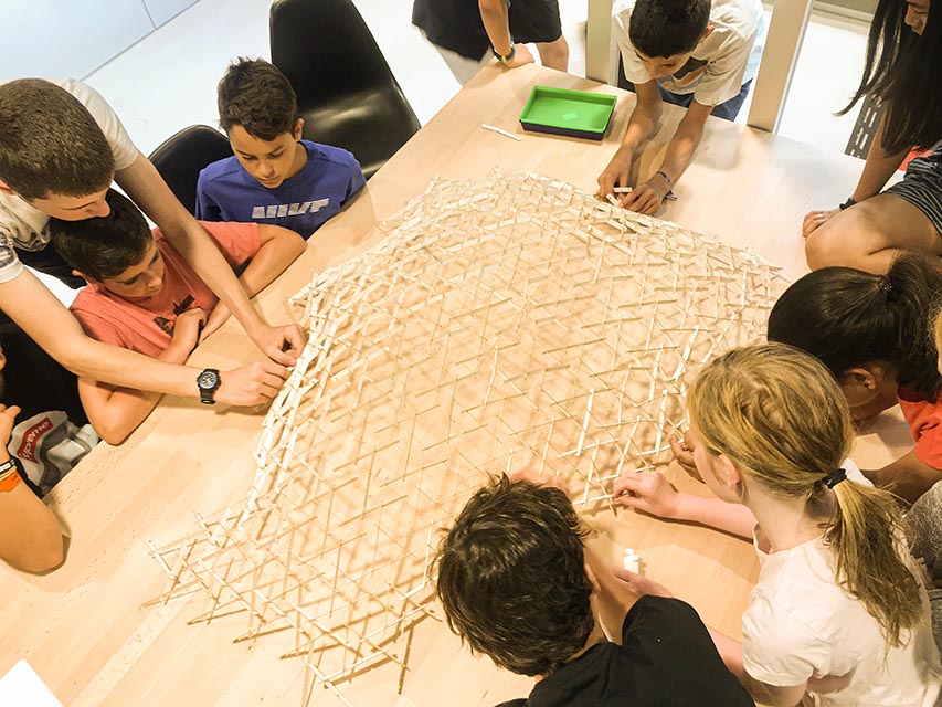 Imagen de un grupo de niños construyendo una 
                      gran estructura con módulos de madera.